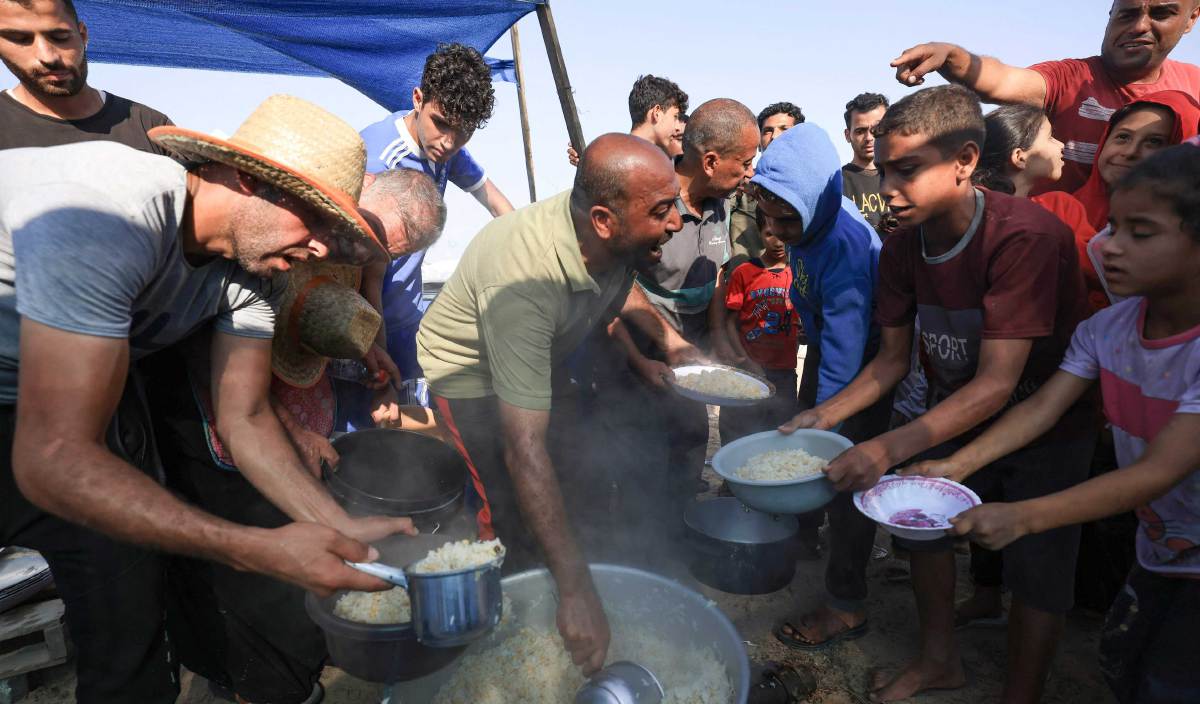 ORANG ramai mengagihkan makanan di kem sementara untuk orang yang kehilangan tempat tinggal di Khan Yunis di selatan Semenanjung Gaza. FOTO AFP
