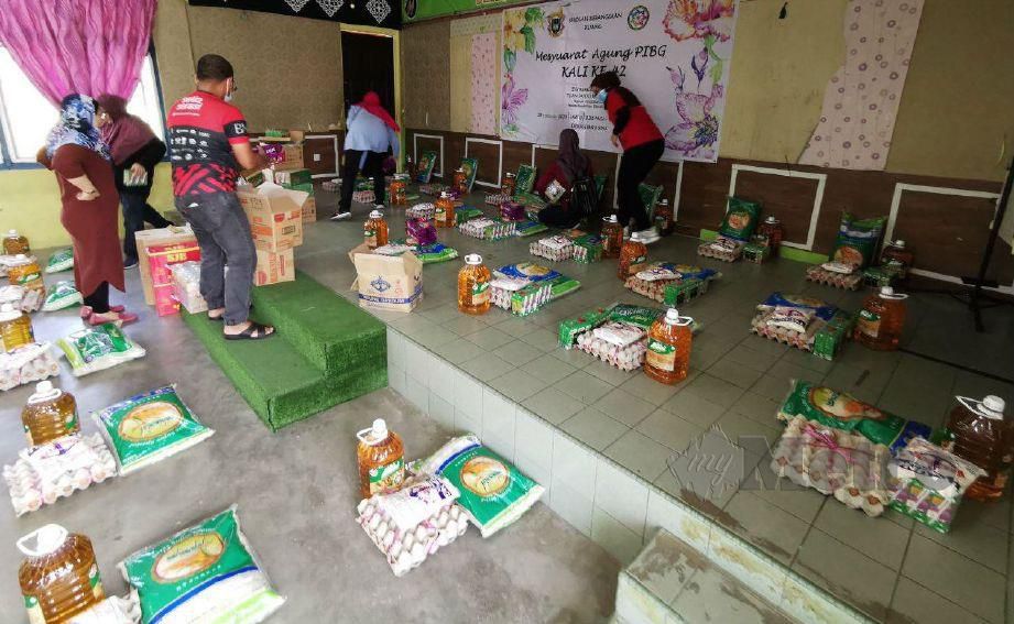 PENYUMBANG menyusun barangan sumbangan sebelum diambil penerima di dewan Sekolah Kebangsaan Kuang. FOTO ihsan Solusi