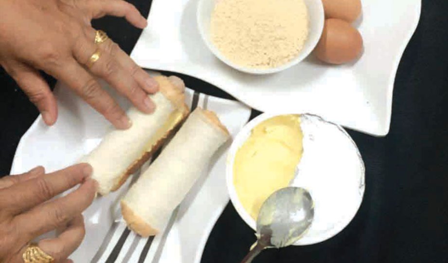 LETAKKAN sosej di atas roti yang sudah disapu mentega tadi dan gulung rapat.