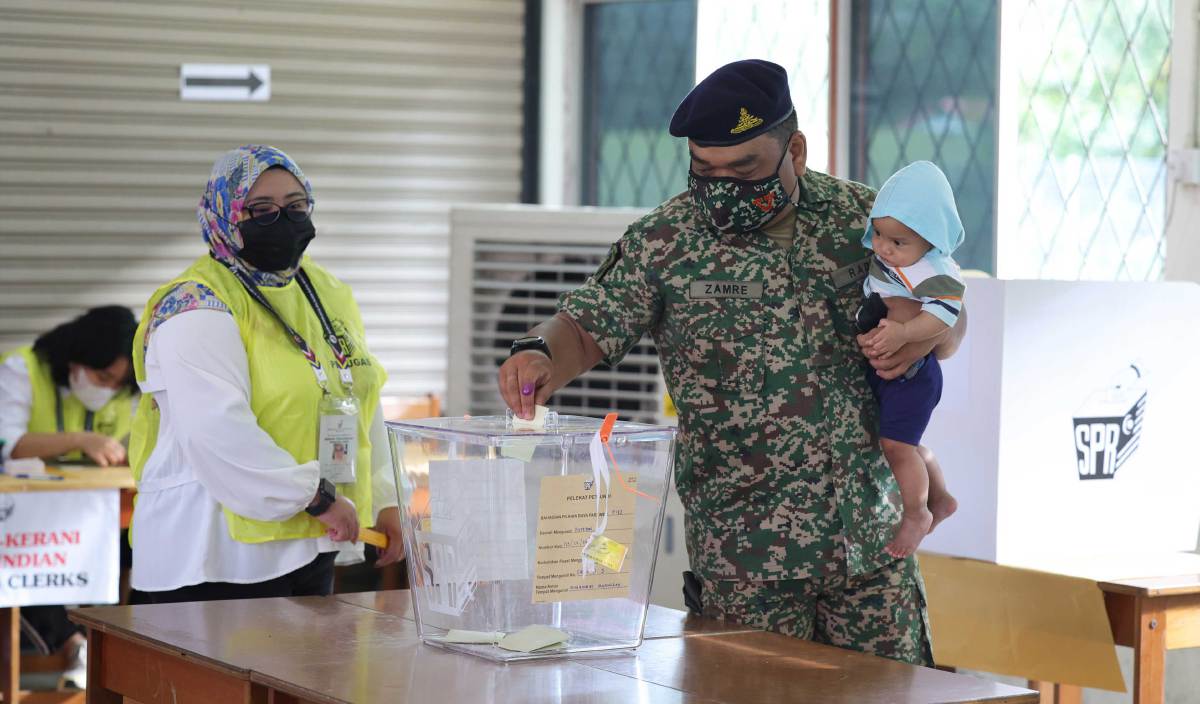 ANGGOTA tentera, Mohd Zamre Rosdi mendukung anaknya untuk menunaikan tanggungjawab mengundi awal bagi memilih pemimpin negara dalam Pilihan Raya Umum Ke-15 (PRU-15) di Kem Lok Kawi. FOTO BERNAMA