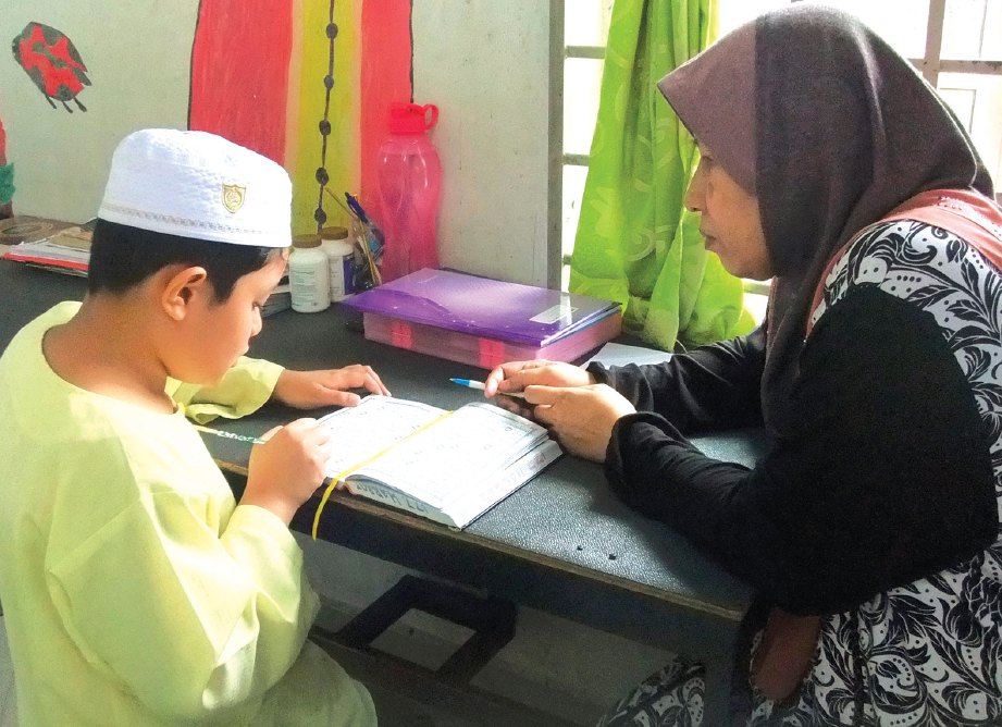 SEORANG pelajar dibimbing guru dalam pengajian al-Quran.