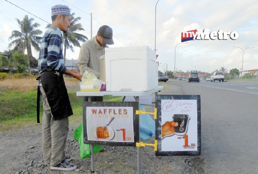 Jaafar Pame, 28, (kiri) dan rakannya, Muhammad Abdullah, 30, melayan pelanggan di tepi jalan berhampiran Taman Fajar yang membeli menu sarapan dengan harga hanya RM1. - Foto Bernama