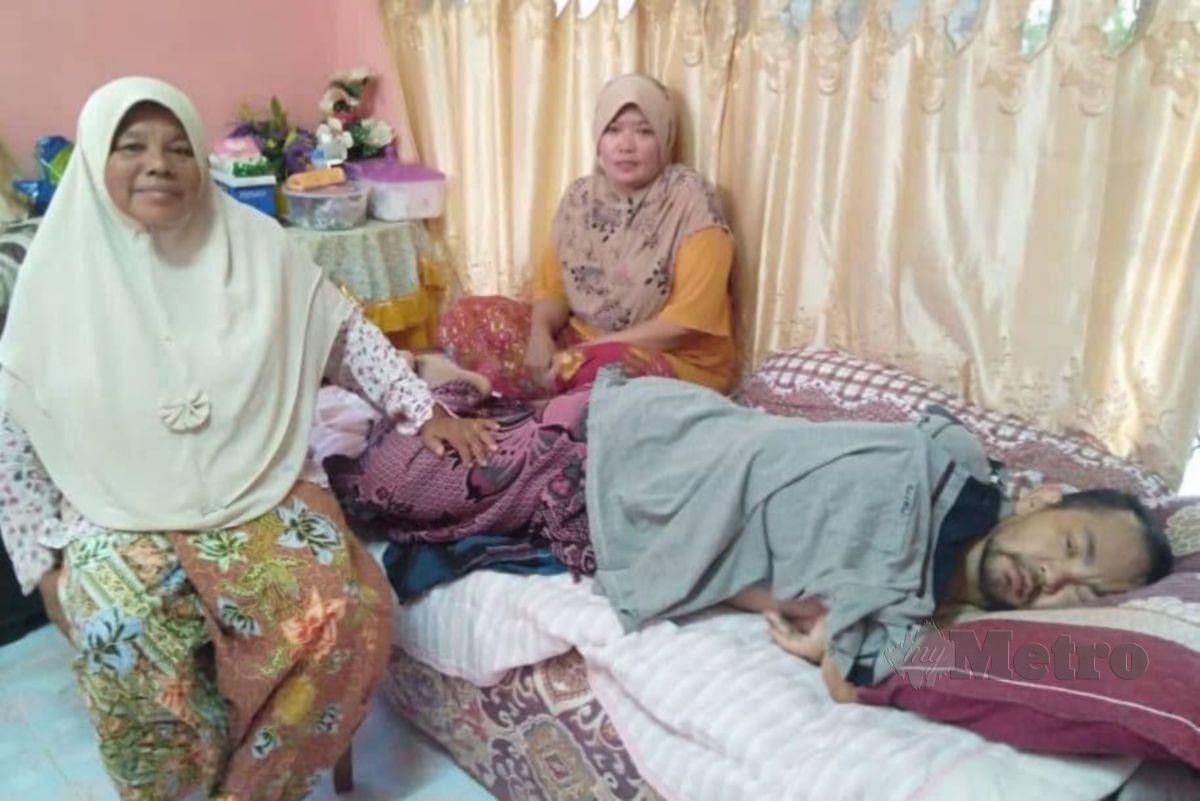 Wati (duduk belakang) dan ibu mentuanya, Raujiah Salleh (kiri) menjaga Mohd Ridzuan yang menghidap  pelbagai jenis penyakit dan cuma terlantar di rumah Felda Kota Gelanggi Dua, Jerantut hari ini. FOTO ROSELAN AB MALEK.