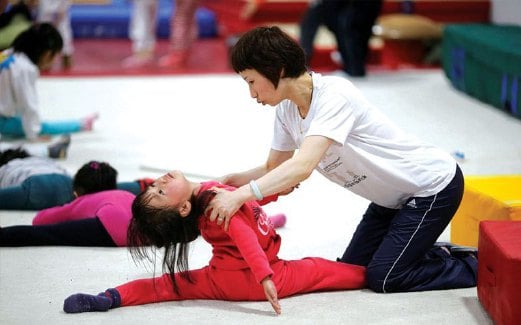 JURULATIH membantu seorang kanak-kanak perempuan ketika latihan gimnastik.