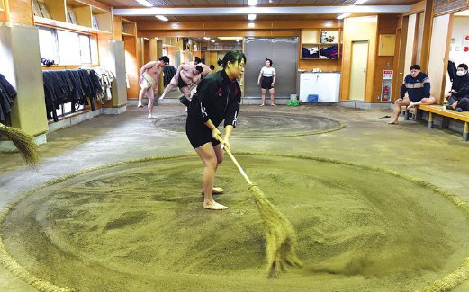AHLI sumo wanita membersihkan dohyo (gelanggang) sebelum berlatih.