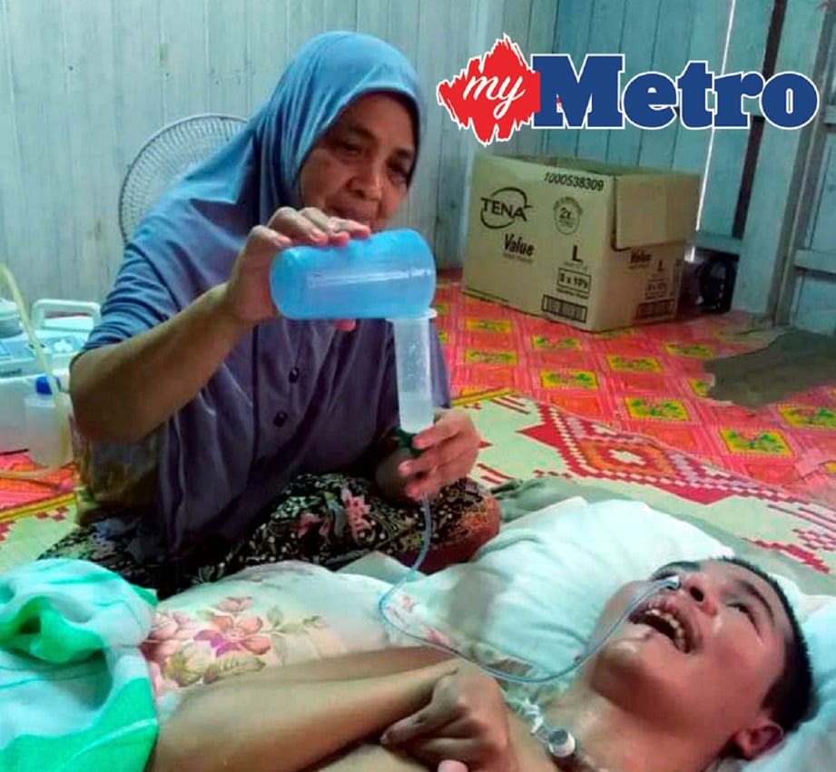 CHE Eshah memberi Muhammad Hazwan minum susu melalui saluran tiub yang dipasang di hidung ketika ditemui di rumahnya di Kampung Padang Durian Tunggal, Banggu. 