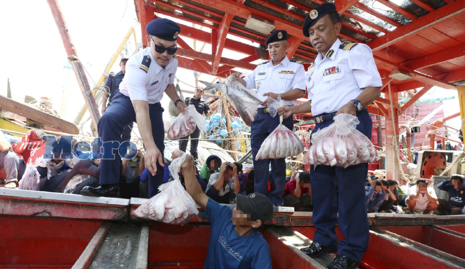 RAHIM (kanan) memeriksa satu bot daripada lima bot nelayan Vietnam yang ditahan di lima lokasi berbeza antara 50 hingga 70 batu Nautika dari muara Kuala Terengganu dan menahan 55 awak-awak termasuk tekong serta membabitkan rampasan bernilai RM5 juta, semalam. FOTO Imran Makhzan. 