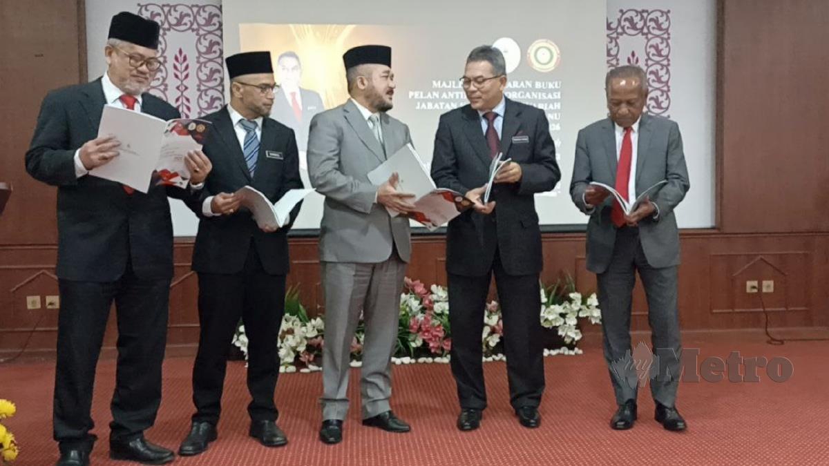 WAN  Mohd Zakri (tengah),  Tengku Farok (dua kanan) dan Pengarah SPRM Terengganu, Ruslan Che Mat (kanan) melihat buku OACP Jabatan Kehakiman Syariah Terengganu. FOTO Zaid Salim.