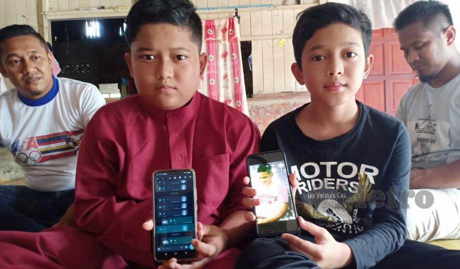 MOHD Shafiq (kiri) dan Mohd Shaqif melihat pesanan suara dan gambar arwah bapanya, Mohd Shahril yang maut dalam kemalangan. FOTO Ahmad Rabiul Zulkifli 