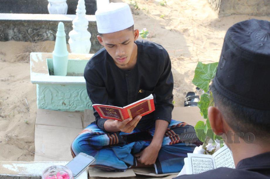 SYAZWAN membaca surah Yasin dan berdoa di pusara arwah isterinya. FOTO Nik Abdullah Nik Omar