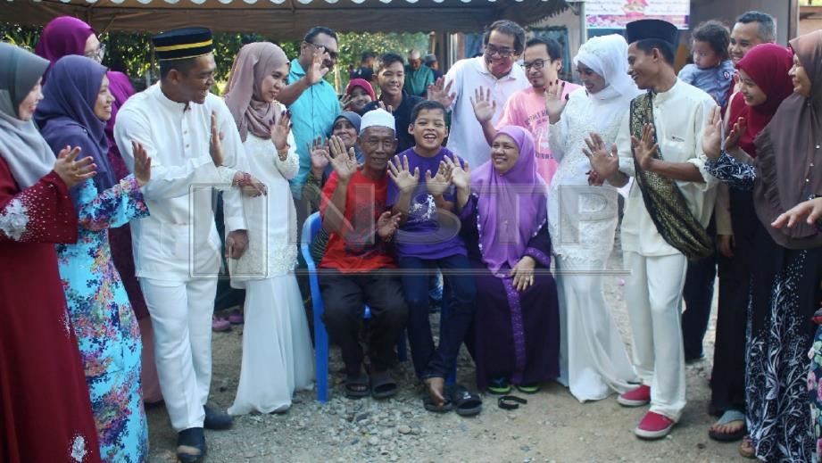 MUHAMMAD Syukur (tengah) bergambar bersama tetamu serta dua abang serta kakak iparnya pada majlis sambut menantu di Kampung Banggol Katong, Kuala Terengganu, hari ini. FOTO Ghazali Kori.