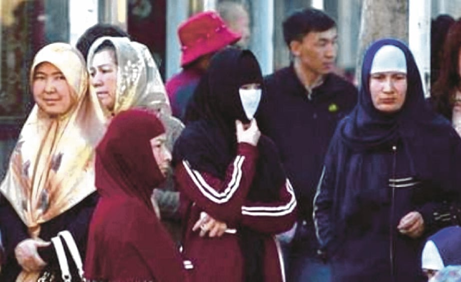 SEKUMPULAN wanita Uighur menunggu bas di Urumqi, Xinjiang.