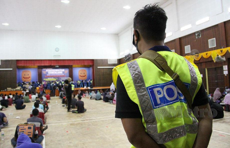 ANGGOTA polis membuat kawalan terhadap 234 tahanan termasuk wanita, kanak-kanak dan bayi yang ditempatkan di Dewan Serbaguna dan Kompleks Sukan Daerah Hulu Selangor, Kuala Kubu Bharu untuk siasatan lanjut. FOTO Halimaton Saadiah Sulaiman