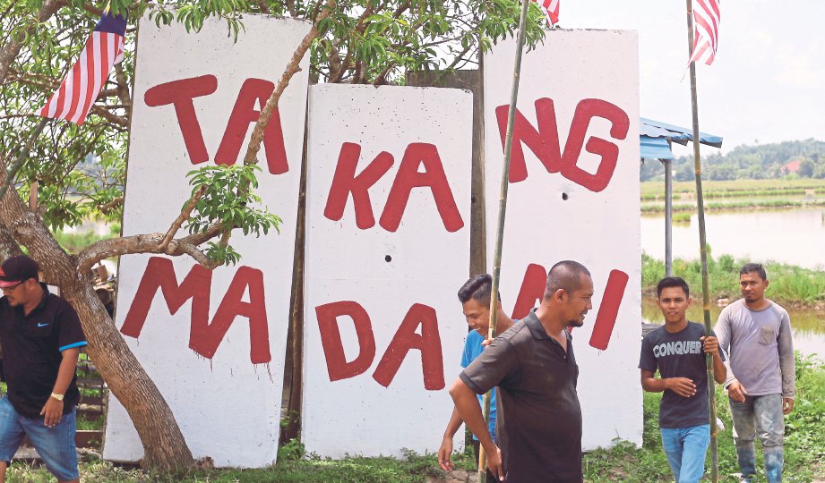  PENDUDUK kampung berkumpul berhampiran logo yang diberi nama Takang Madani.