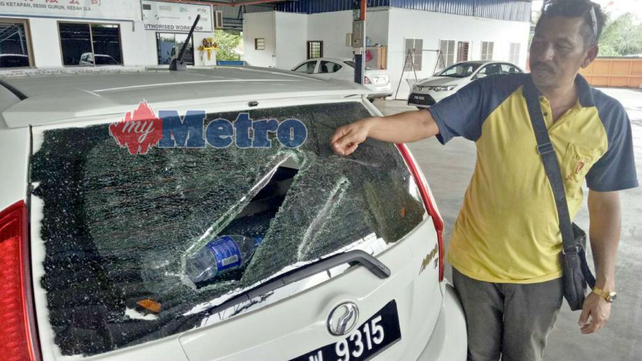 Mohamad  menunjukkan cermin belakang kereta miliknya yang pecah akibat ditetak bekas rakan sekerja. FOTO Nur Syazwana Mansor