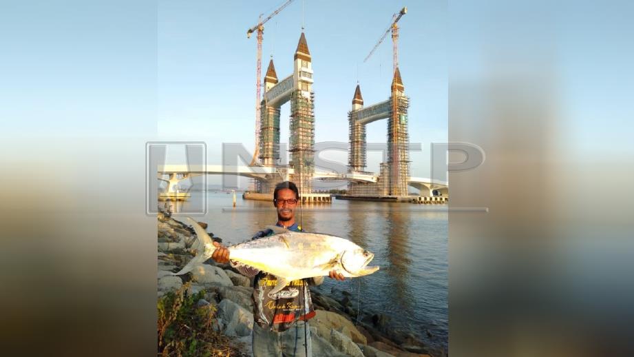 ZAKARIA menunjukkan ikan talang seberat 6.3kg berjaya dipancing di benteng pemecah ombak Tanjung berdekatan jambatan angkat di muara selatan Bandaraya Kuala Terengganu, kelmarin. FOTO Ahmad Rabiul Zulkifli. 