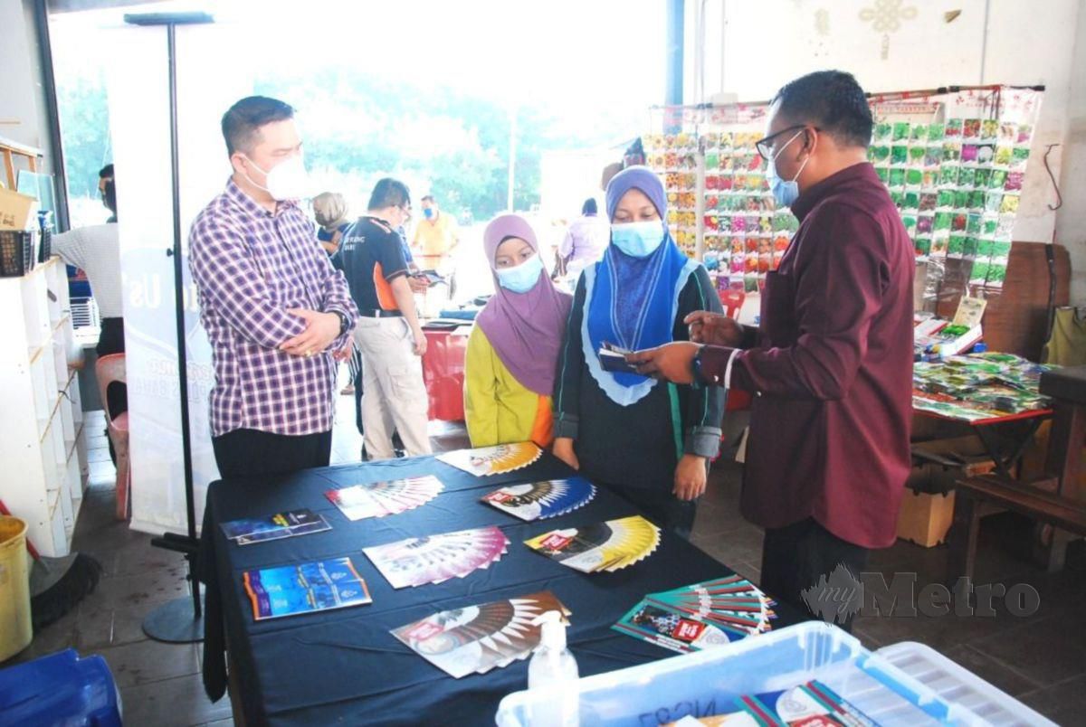 HOO (kiri) ketika meninjau pameran sempena program Talk To Us di Pasar Borong Bahau. FOTO Abnor Hamizam Abd Manap