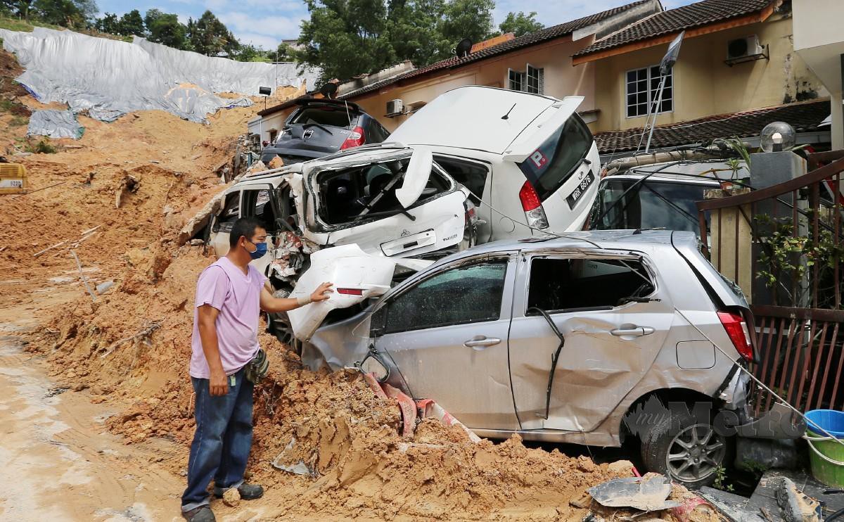 Penduduk Taman Bukit Permai 2, Tan Kok Meng, 43, melihat keretanya yang rosak teruk akibat tanah runtuh. FOTO SAIFULLIZAN TAMADI
