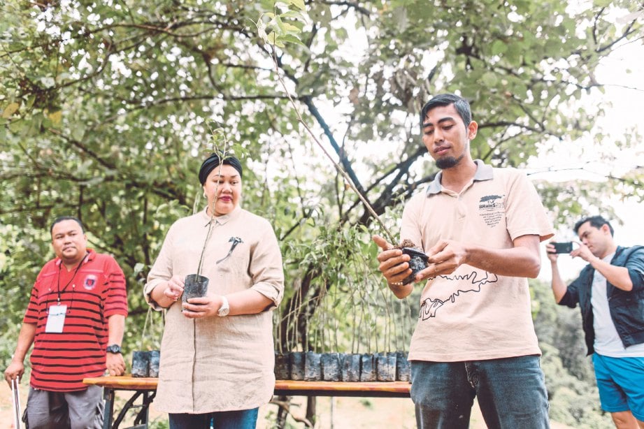 FAZWINNA (tengah) mendengar penerangan Pegawai Penyelidik Pusat Penyelidikan Hutan Hujan Pulau Banding Mohd Syaiful Mohammad sebelum menanam pokok gaharu.