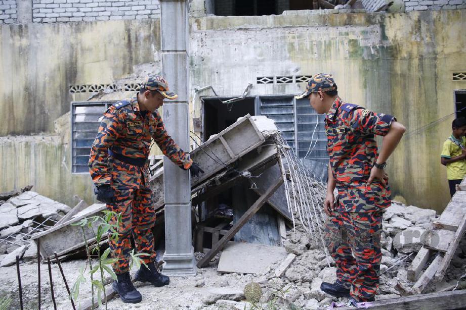Razali (kiri) melihat keadaan tangga  runtuh yang mengorbankan empat mangsa di Kampung Matang Pagar, Sungai Buloh. FOTO Syarafiq Abd Samad 