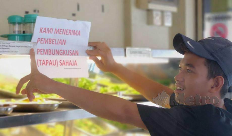 PEKERJA sebuah kedai makan di Satok menampal notis pemberitahuan di kedainya. FOTO Mohd Roji Kawi