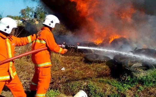 DUA anggota bomba berusaha memadamkan kebakaran pada longgokan tayar di Taman Seri Kota, Bestari Jaya, semalam.