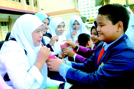  Norhanani Said (kiri)  bersama guru Sekolah Kebangsaan Langkawi yang lengkap berpakaian seragam sekolah disajikan segelas air sirap yang manis sebagai tanda kasih murid kepada guru.