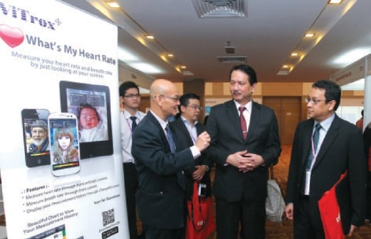 DR Wong (kiri) menjelaskan kepada Dr Noor Hisham mengenai aplikasi telefon pintar yang mengesan kadar denyutan jantung.