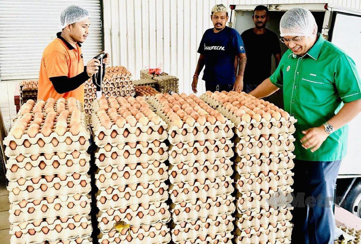 Dr Azman (kanan) melihat telur ayam dikeluarkan syarikat ladang ternakan ayam penelur dimiliki anak jati negeri ini di Kalumpang, Hulu Selangor, semalam. FOTO BAHAROM BAKAR