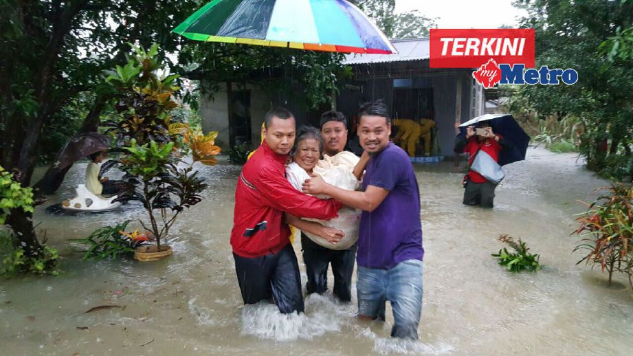 Penduduk Kampung Pasir Akar, Hulu Besut membantu mengusung warga emas, Lijah Musa,75 yang lumpuh untuk dihantar ke pusat pemindahan. FOTO Mohammad Ishak.