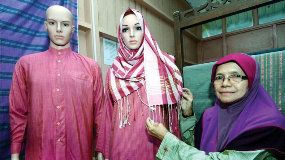 ZAINABON bersama koleksi fesyen Tenun Pahang Diraja yang dipamerkan di bengkelnya di Kampung Temai Hilir.