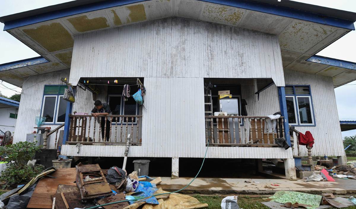 MUHAMMAD Shafiq melihat barangan dalam rumah keluarganya yang terpaksa dibuang kerana rosak akibat banjir di Kampung Kuala Jengal, Dungun. FOTO BERNAMA