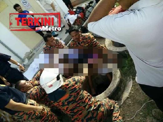 Anggota bomba mengangkat budak perempuan yang meninggal dunia selepas terjatuh ke dalam lubang kumbahan. FOTO ihsan pembaca 