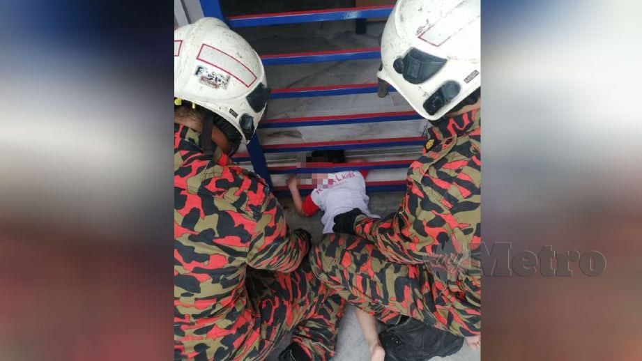 ANGGOTA bomba membantu mengeluarkan kepala kanak-kanak yang tersepit. FOTO ihsan Bomba. 