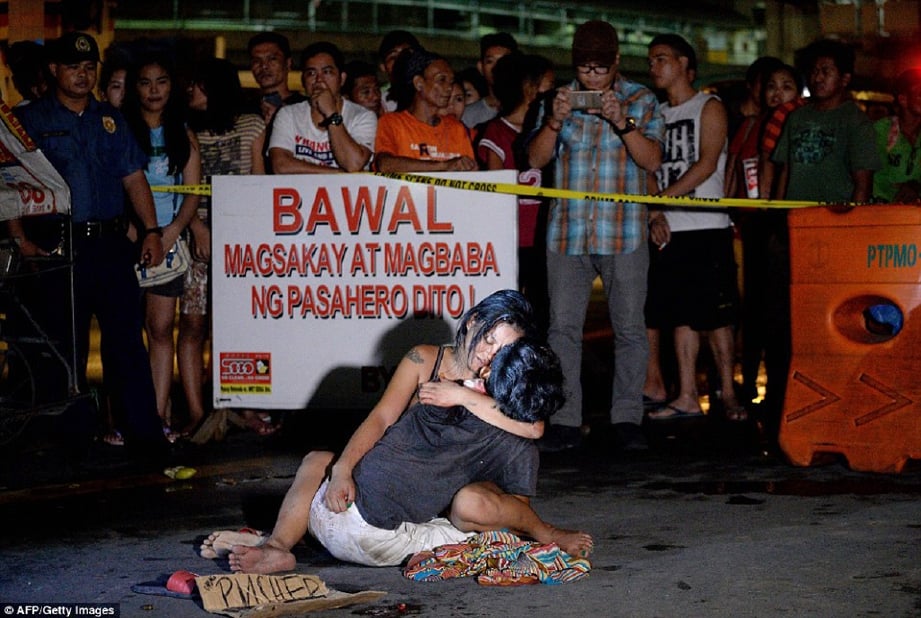 Gambar pada 23 Julai lalu, menunjukkan seorang wanita memeluk mayat suaminya yang mati ditembak individu tidak dikenali di Manila. - AFP