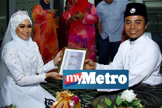 ABDUL Muniff Md Isa menyerahkan mas kahwin kepada Mas Normuharni Sheikhah Mohd Sattar selepas majlis akad nikah di Masjid Bandar Puteri Jaya. FOTO Omar Osman