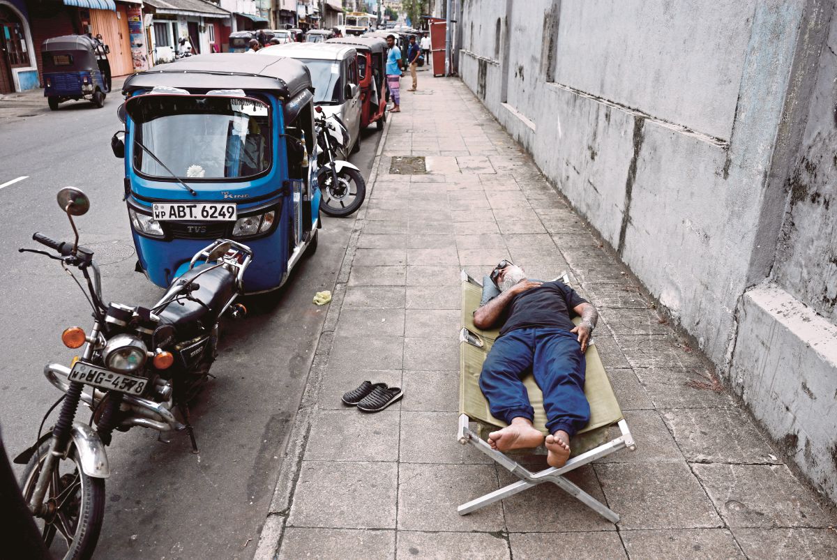 LELAKI tidur di kaki lima sementara menunggu giliran untuk membeli petrol di Sri Lanka. FOTO Reuters