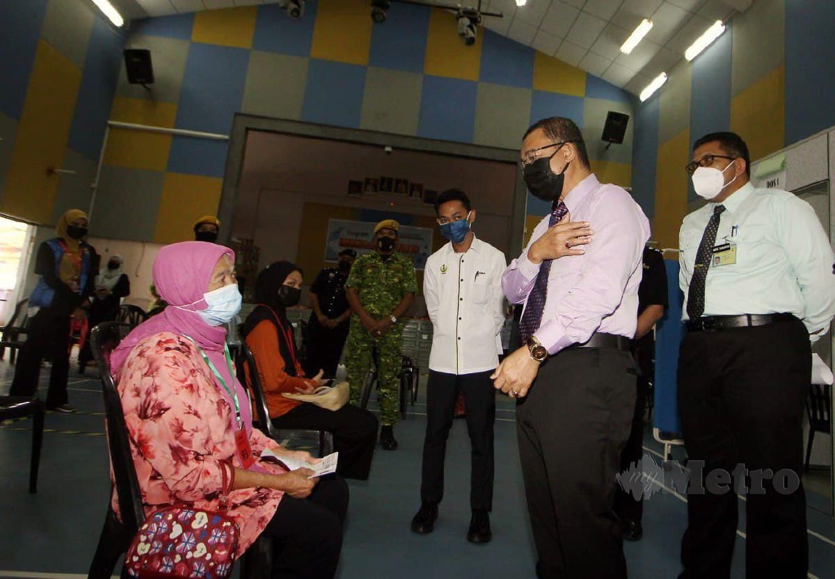 Dr Noor Azmi (kanan) beramah mesra bersama penerima vaksin  ketika hadir lawatan kerja di Pusat Penerimaan Vaksin (PPV) di Dewan Merdeka, Lenggong. FOTO SHARUL HAFIZ ZAM