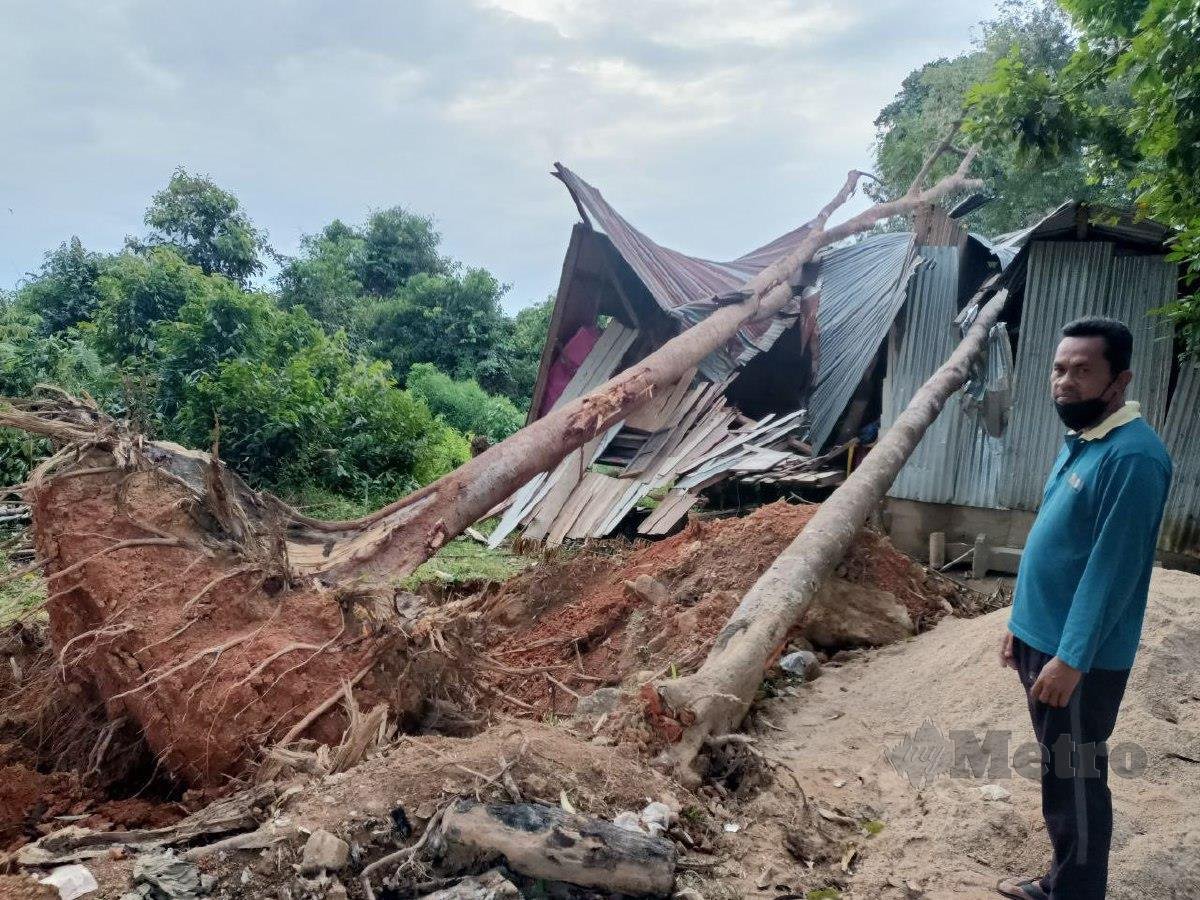 ASMAWI melihat rumahnya yang musnah akibat dihempap dua batang pokok. FOTO Siti Rohana Idris