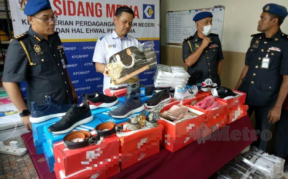 SAHARUDDIN (dua dari kiri) menunjukkan pelbagai barangan tiruan yang dirampas dalam Ops Jeriji Cap Dagang di Chendering, Kuala Terengganu, hari ini. FOTO BAHAROM BAKAR