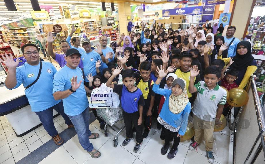 HUSAIN (dua dari kiri) bersama 150 murid dari enam sekolah sekitar Kuala Terengganu dan Marang membeli peralatan sekolah sempena program Titipan Kasih Kembali Ke Sekolah di Mydin Mall, Kuala Terengganu. FOTO Ghazali Kori 