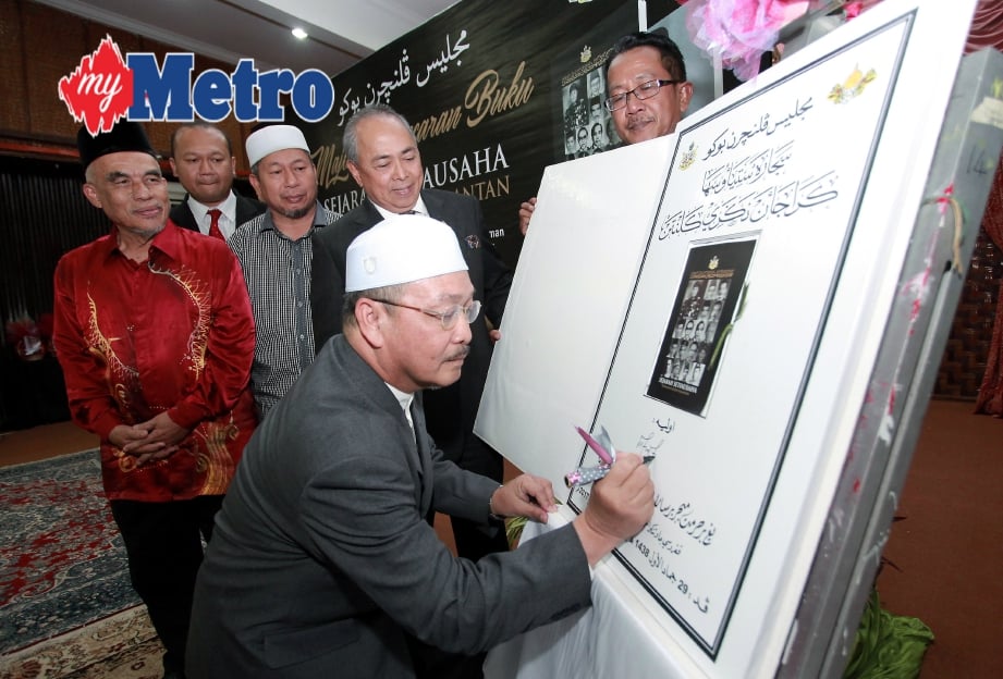 Md Anizam menurunkan tandatangan sebagai simbolik pelancaran buku Sejarah SUK Kelantan. FOTO Faris Zainuldin
