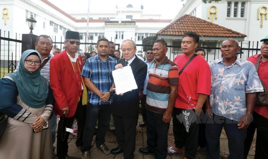 KAMARUDIN (tengah) yang mewakili keluarga mangsa gas toksik Pasir Gudang menunjukkan saman yang difailkan di Mahkamah Tinggi Johor Bahru. FOTO Hairul Anuar Rahim