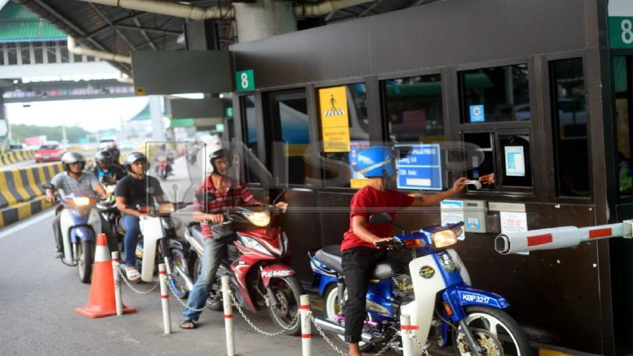 PENUNGGANG motosikal membayar tol di Jambatan Pulau Pinang, hari ini. Foto SHAHNAZ FAZLIE SHAHRIZAL