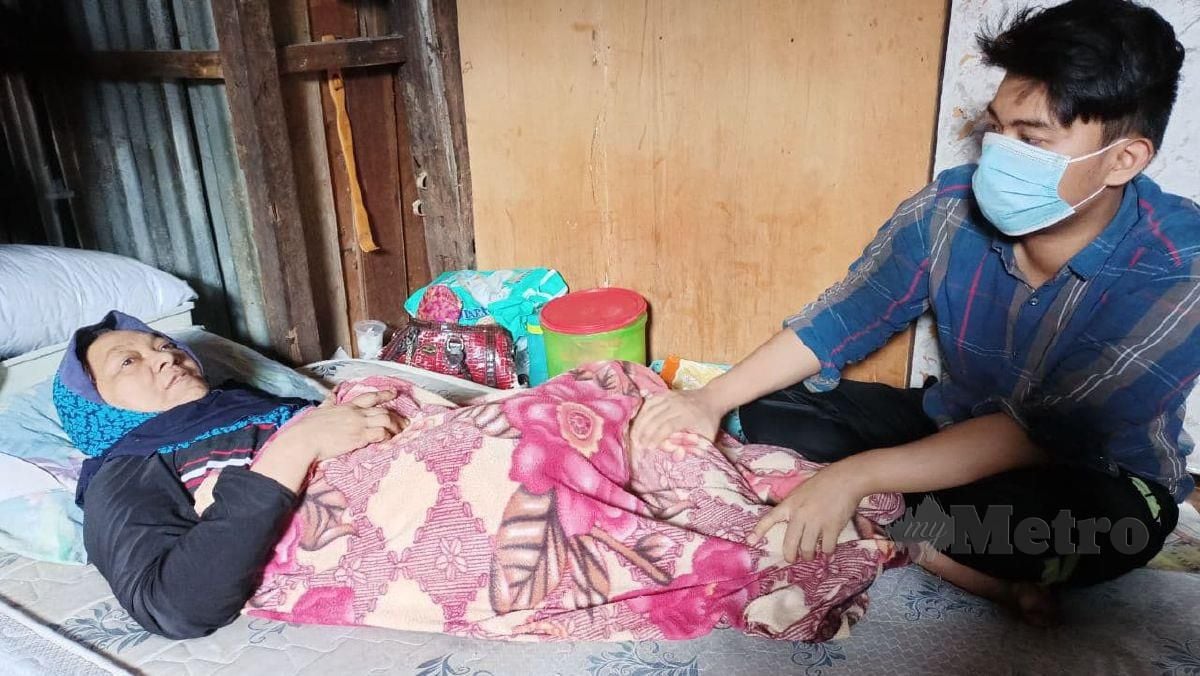 CHE Muhammad menjaga ibunya Junaidah Ismail yang terlantar akibat strok di rumahnya di Kampung Cina. FOTO SITI ROHANA IDRIS