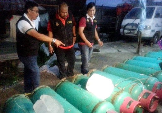 ANGGOTA penguat kuasa memeriksa tong gas yang dirampas dalam serbuan di Kampung Bohol. 