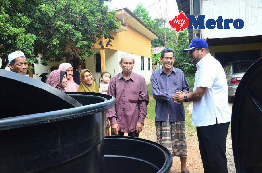 Shaiful (kanan) menyampaikan tangki air kepada penduduk di kawasan Pedu, Padang Terap. 