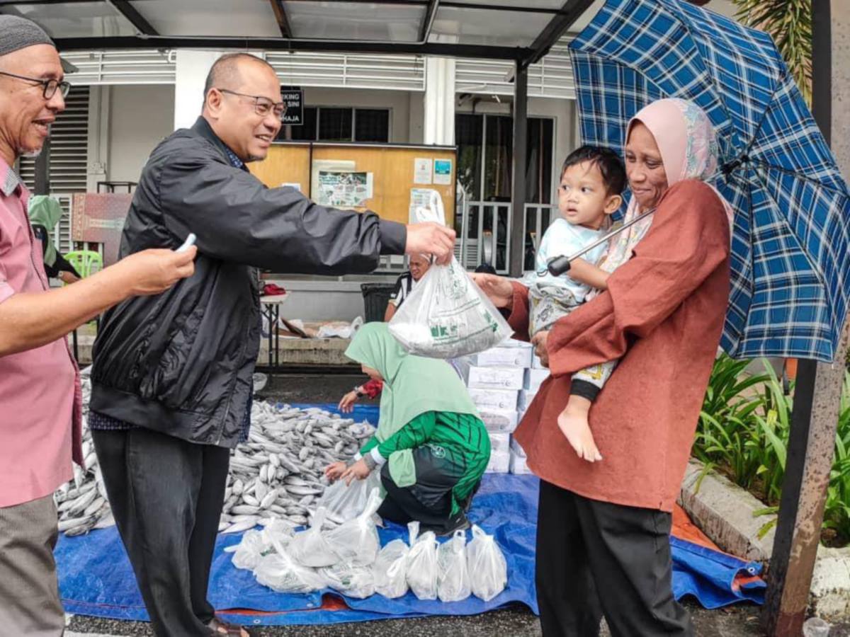 Ahmad Amzad  mengagihkan ikan tongkol kepada penduduk Projek Perumahan Rakyat (PPR) Padang Hiliran. FOTO IHSAN FB AHMAD AMZAD HASHIM
