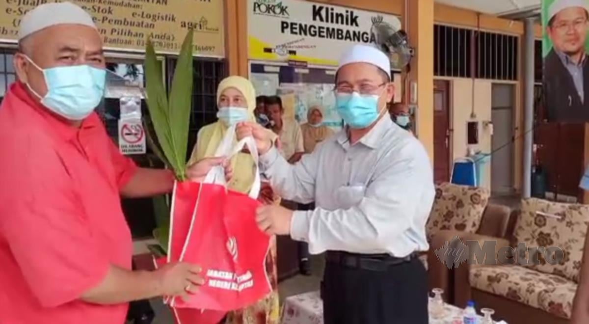 Tuan Mohd Saripudin Tuan Ismail (tengah) menyerahkan anak pokok kelapa pandan kepada penerima ketika majlis penyerahan tanam kelapa Al- Falah di Pejabat Jabatan Pertanian Daerah Pasir Puteh. FOTO / Nor Amalina Alias 