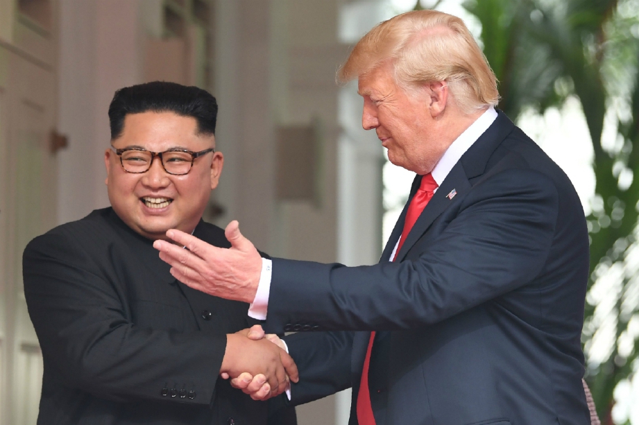 Trump berjabat tangan dengan Jong Un (kiri). FOTO AFP 